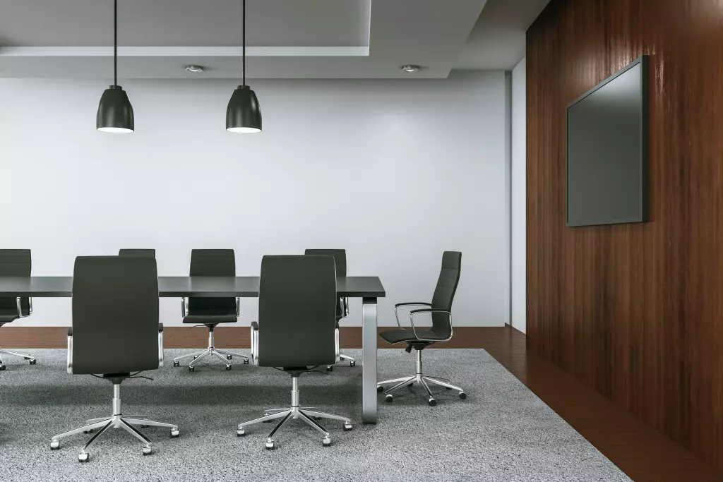 Modern conference room with a large rectangle table surrounded by black ergonomic chairs.