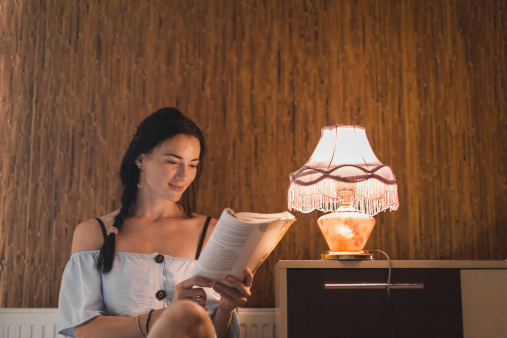 young woman reading book near illuminated light lamp scaled - Interior Design American Style